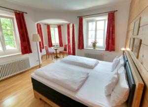 a bedroom with a large white bed with red curtains at Hotel Terofal in Schliersee