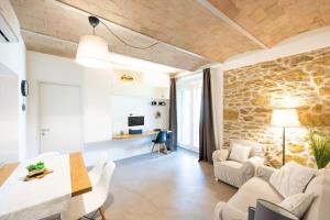 a living room with white furniture and a stone wall at Appartamento il Poggino in Colle di Val d'Elsa
