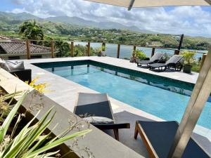 a swimming pool with chairs and a view of the water at Villa Adina - A luxury villa with pool, perfect for a quiet hideaway or an exotic escape in Westerhall Land Settlement
