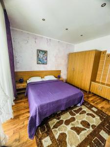 a bedroom with a purple bed and a rug at Vila Orange in Mamaia Nord