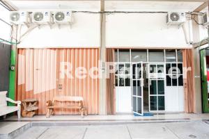 a building with a door and a bench outside at Happy Inn Puspo Mitra RedDoorz in Jomblang