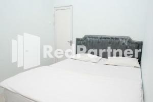 a white bedroom with a bed with a red partner sign on it at Happy Inn Puspo Mitra RedDoorz in Jomblang