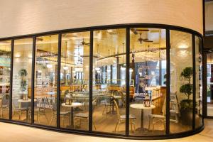 un restaurant avec des baies vitrées, des tables et des chaises dans l'établissement Bunga Suite at Lucentia BBCC, à Kuala Lumpur