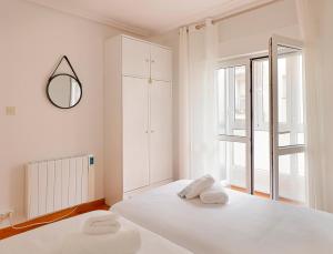 een witte slaapkamer met een bed en een spiegel bij 142A Apto 2 habitaciones Playa San Lorenzo in Gijón