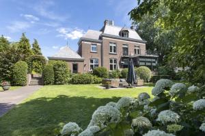 una casa grande con un patio con flores en Stylish Guesthouse with 2 Free E-bikes - near Breda!, en Etten-Leur