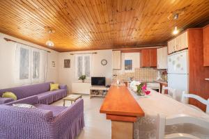 a living room with purple couches and a kitchen at Pitoros Summer Cottage Kefalonia in Mesovoúnia