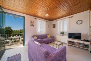 a living room with purple furniture and a balcony at Pitoros Summer Cottage Kefalonia in Mesovoúnia