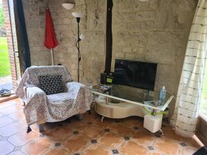 a living room with a chair and a tv at Petite Maison de campagne in Fauguernon