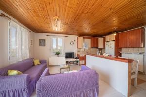 a living room with purple couches and a kitchen at Pitoros Summer Cottage Kefalonia in Mesovoúnia