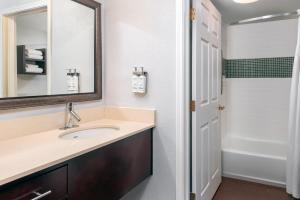uma casa de banho com um lavatório, um espelho e uma banheira em Staybridge Suites Miami Doral Area, an IHG Hotel em Miami