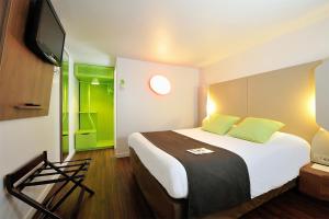 ein Hotelzimmer mit einem großen Bett und einem TV in der Unterkunft Campanile Bollène A7 in Bollène
