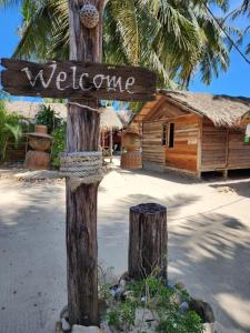 a wooden sign on a tree with a welcome sign at Castaway Beach Bungalows in Srithanu +60 photos