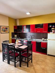 une cuisine avec des placards rouges, une table et des chaises dans l'établissement Seaview Apartment, Durres Beach, à Durrës