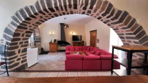 uma sala de estar com um sofá vermelho sob um arco em Relais du Noble Voyageur em Brioude