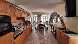 a kitchen with wooden cabinets and a dining room at Relais du Noble Voyageur in Brioude