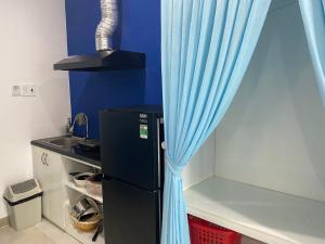 a black refrigerator with a blue curtain in a kitchen at Alicia Hotel in Tuy Hoa