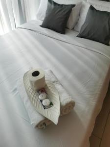 ein weißes Bett mit Handtüchern und einer Rolle Toilettenpapier in der Unterkunft Sunshine Properties at One Uptown BGC in Manila