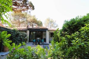 a house with a table and chairs in a garden at GASSPON - Golfe de St-Tropez - Mazet dans domaine privé avec piscine et tennis in Cogolin