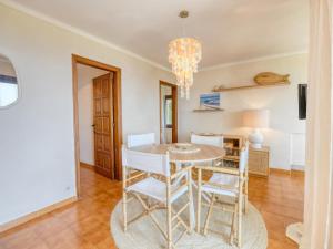 uma sala de jantar com uma mesa e cadeiras e um lustre em apartament amb piscina comunitària al Golfet em Calella de Palafrugell
