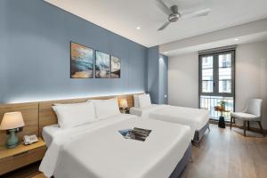 a hotel room with two beds and a chair at Laputa Hotel Phú Quốc in Phú Quốc