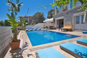 une piscine avec chaises longues et une maison dans l'établissement İonic Alaçatı, à Çeşme