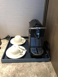 een koffiezetapparaat met 2 witte gerechten op een dienblad bij Foshan Marriott Hotel in Foshan