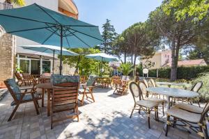a patio with tables and chairs and an umbrella at Minerva Hotel in Medulin