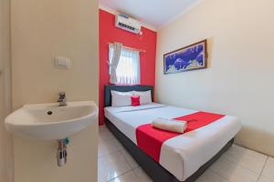 um pequeno quarto com uma cama e um lavatório em RedDoorz Syariah at Sudirman Street Garut em Garut