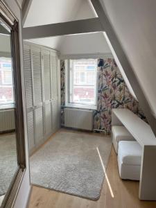 een kleine zolderkamer met een bank en ramen bij Het Popelhuisje in Alkmaar