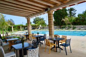 a patio with tables and chairs next to a swimming pool at Agriturismo Masseria del Bosco Makyva in Borgagne