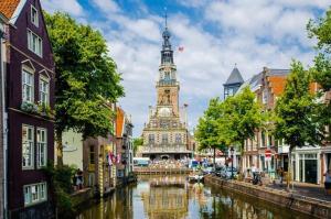 um edifício com uma torre de relógio ao lado de um rio em Het Popelhuisje em Alkmaar