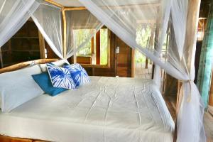 a bedroom with a canopy bed with blue and white pillows at Private Beachfront House with Kayak & Guided Tours in Changuinola