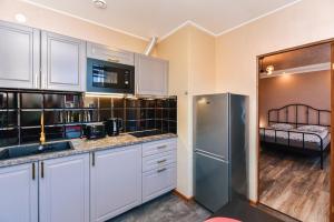 a kitchen with white cabinets and a stainless steel refrigerator at Meldernams in Ventspils