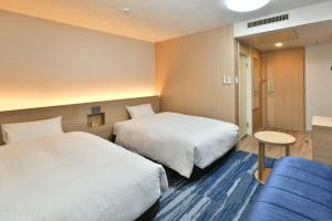 um quarto de hotel com duas camas e um sofá azul em Nagoya Sakae Washington Hotel Plaza em Nagoia