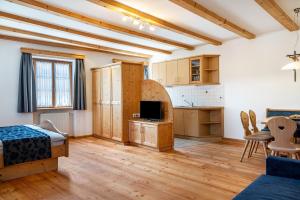 a room with a bedroom and a kitchen with wooden floors at Schreiberhof Landhaus in Laion