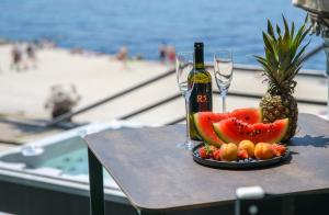 Via Mare Luxury Rooms في سبليت: طاولة مع صحن من الفواكه وزجاجة من النبيذ