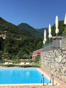 a swimming pool with chairs and a stone wall at Villa San Sisinnio Argegno in Argegno