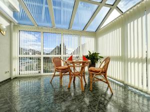 un salón acristalado con mesa y sillas en una habitación con ventanas en Pension Böhm, en Seligenthal