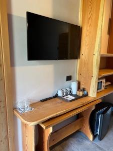 a wooden table with a television on a wall at B&B Casa il sasso in Pinzolo