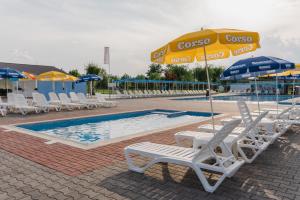 ein Schwimmbecken mit Stühlen und Sonnenschirmen neben einem Schwimmbecken in der Unterkunft COMPLEX AGREMENT BELLAVI in Ocna-Mureşului