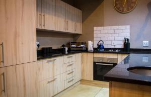 a kitchen with wooden cabinets and a clock on the wall at Fairfarren in Hoedspruit