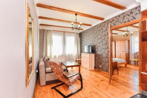 Una sala de estar con una silla y un espejo. en Villa Victoria, en Ventspils