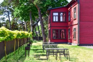 un grupo de mesas frente a un edificio rojo en Villa Victoria, en Ventspils