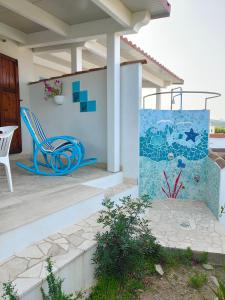un patio con una silla azul y una pared de mosaico en Casa Vacanze Miranda, en Torre dei Corsari