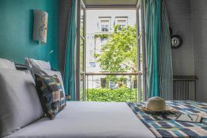 una cama con un sombrero de paja sentado en ella frente a una ventana en Mercure Paris Opera Grands Boulevards, en París