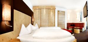 1 Schlafzimmer mit 2 weißen Betten in einem Zimmer in der Unterkunft Hotel Störes - Living Nature Hotel in St. Kassian