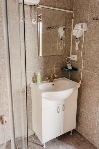 W łazience znajduje się biała umywalka i lustro. w obiekcie COMPLEX AGREMENT BELLAVI w mieście Ocna Mureş