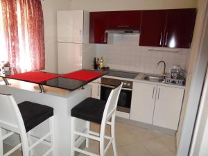 a kitchen with white cabinets and a counter with stools at Apartma Istra Zora in Sečovlje