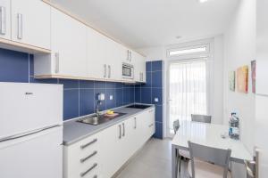 a kitchen with white appliances and a table with chairs at Lightbooking Sun Club deluxe Playa del Ingles in Playa del Ingles