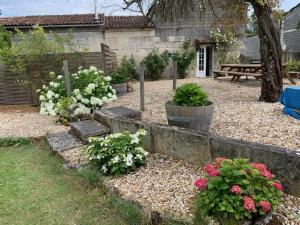 a garden with flowers and plants in front of a house at La Cour des Cloches in Mainxe